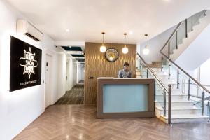 新德里Skon Boutique by Orion Hotels的站在走廊上楼梯的柜台上的人