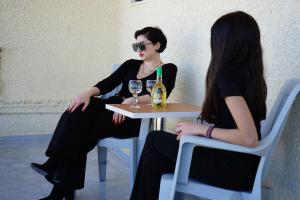 a woman sitting at a table with a bottle of wine at ROMANTZA apartments in Agia Marina Nea Kydonias