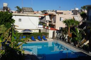 a view of a swimming pool with chairs and buildings at ROMANTZA apartments in Agia Marina Nea Kydonias
