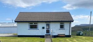 a small white house with a bench in front of it at Almondbank Cottage - 2 Bedrooms, 8 miles from Portree in Skeabost