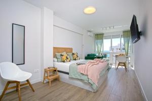 ein weißes Schlafzimmer mit einem Bett und einem Stuhl in der Unterkunft Sunstay Cruz Loft Torremolinos in Torremolinos