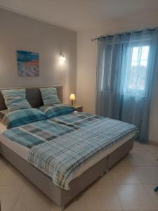 a bedroom with a bed with a blue comforter and a window at Willa Ferry **** in Prizna +119 photos