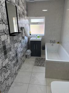 a bathroom with a tub and a sink at Luxurious 3 bedrooms flat near New Cross,Wolverhampton No Parties or events in Wednesfield