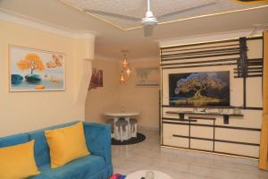 ein Wohnzimmer mit einem blauen Sofa und einem Fernseher in der Unterkunft Beautiful Spaces 3 bedroomed bungalow in Kira