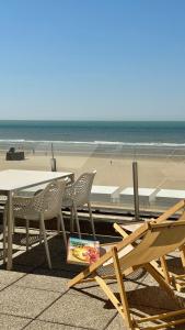 a table and chairs next to a beach at Seanest - North Sea Stays in De Haan
