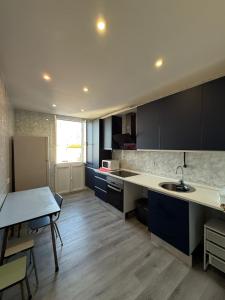 eine Küche mit schwarzen Schränken, einem Tisch und einem Waschbecken in der Unterkunft Amplio piso para 17 en pleno centro de Madrid in Madrid + 24 Fotos
