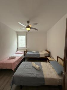 Zimmer mit 3 Betten und einem Deckenventilator in der Unterkunft Amplio piso para 17 en pleno centro de Madrid in Madrid