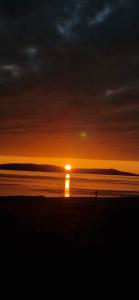 葛特纳格林Greenatang,Shapinsay,Orkney的海滩上的日落,阳光在水中反射