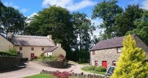 een groot wit huis met rode deuren in een tuin bij Granary Cottage with hot tub on organic farmland in Lampeter