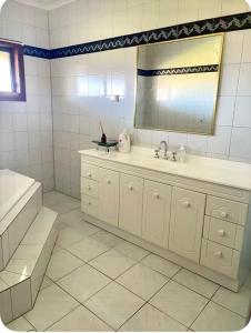 a bathroom with a sink and a mirror and a tub at Farm house in Monash