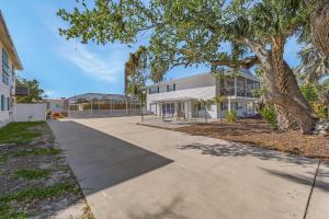an empty sidewalk in front of a building with a tree at 140 Barefoot Bungalow- 4BR 2BA with Heated Pool! home in Fort Myers Beach