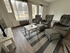 a living room with chairs and a tv and a table at Puomitie for 3 persons in Kajaani