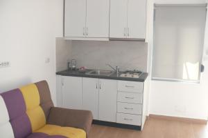 a kitchen with white cabinets and a sink and a couch at Hotel Erviliano in Borsh