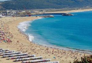 a group of people on a beach with umbrellas at Flipflops Apartment in Nazaré