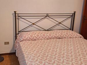 un letto con testiera metallica in una camera da letto di La Casetta nel Borgo a Mezzana Altre 10 foto