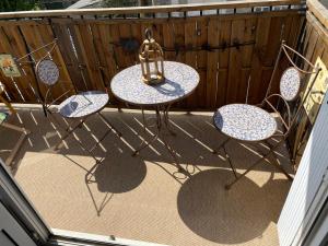 un patio con tre sedie e un tavolo con una lanterna di Superbe appartement à 5min du centre-ville a Dinan
