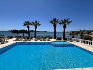 a large swimming pool with palm trees and the water at cunda panorama otel in Ayvalık
