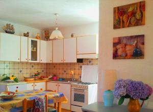 a kitchen with white cabinets and a table with purple flowers at La Terrazza in Barano d'Ischia
