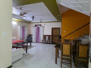 ein Wohnzimmer mit einer Couch sowie Tischen und Stühlen in der Unterkunft VilleFortune 3BHK Cottage In Nainital in Bhīm Tāl