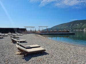 a row of chaise lounges on a beach next to the water at Apartman Mano in Topla