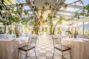 un salón de banquetes con mesas, sillas y plantas en Villa Sasso en Merano