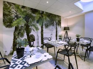 a restaurant with tables and chairs and palm trees on the wall at L'aparthoteL LhL in Dijon
