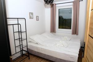 a small bedroom with a white bed and a window at Domki w Winnicy - Świętokrzyska Winnica Knapów in Krzczonowice