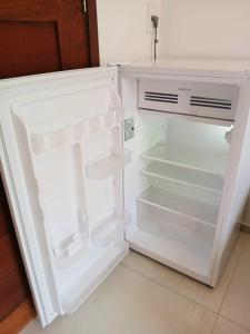 an empty refrigerator with its door open in a kitchen at 2 COCO BAMBU PIPA apto 2, a 200 metros da praia e a 100 metros do centro in Pipa