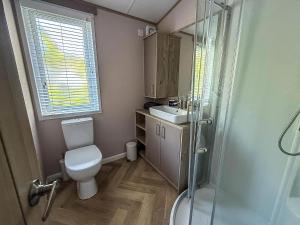 a bathroom with a toilet and a sink and a shower at Beautiful Lodge With Decking At Azure Seas In Suffolk, Sleeps 6 Ref 32217Og in Lowestoft +16 photos