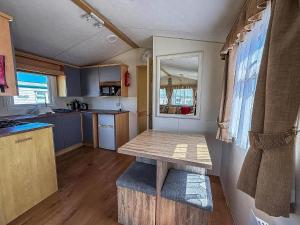 a kitchen with a wooden table in a tiny house at Superb Caravan With Decking At Kessingland Beach In Norfolk Ref 90038Td in Benacre
