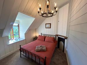 a bedroom with a red bed with a chandelier at Panoramic Mountain Retreat - Waen Fechan - 4x4 access only in Dolgellau