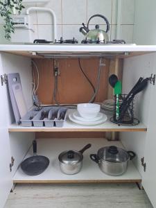 a kitchen shelf with pots and pans and a sink at Baznicas Str Apartments in Liepāja