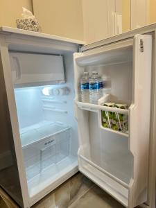 an open refrigerator with bottles of water in it at Modern Studio Luxe Heathrow London in New Bedfont +26 photos