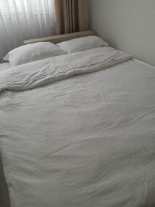 an unmade bed with white sheets and pillows at City Center Moku Apartman in Zenica