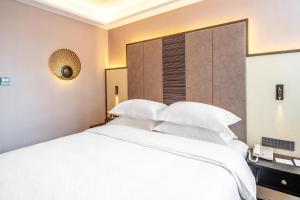 Rúm í herbergi á Shenzhen Longgang Central City Jinjiang Metropolo Hotel