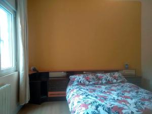 Un dormitorio con una cama con colcha floral y una ventana. en Plaza Mayor de León 3º sin ascensor, en León