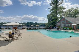 una piscina con tavoli e sedie e un edificio di Lake Access and Pools Sun-Soaked Westford Cottage! a Westford