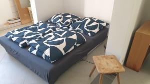 a bed with black and white sheets and a wooden stool at Luessishausen im Lüsserttal mit 140m2 und DSL in Feilbingert