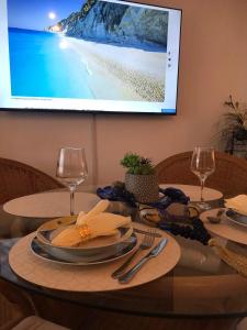 een tafel met twee wijnglazen en een projectie van een strand bij ARIS House in Agia Paraskevi