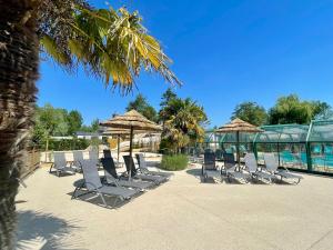 a row of chairs and umbrellas on a patio at Camping Les Tourterelles in Rang-du-Fliers