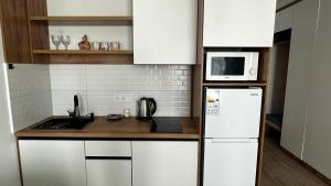 a kitchen with a white refrigerator and a microwave at Флора in Almaty +6 photos
