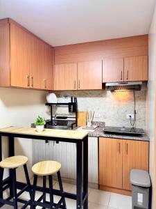 a kitchen with wooden cabinets and a counter with stools at VR Homes Ortigas - 2BR Condo with Free WiFi in Manila