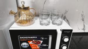 Una licuadora y dos vasos encima de un microondas en The Apartment, en Tashkent