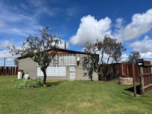 a house with a fence and a tree in a yard at Green Thumb Farm Stay in Ermelo