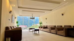 a waiting room with brown leather couches and a table at Florid Hotel and Resort Kalam in Kalām