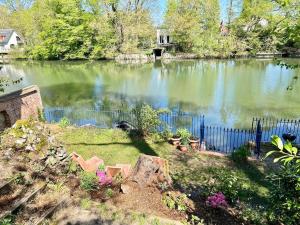 een vijver met een hek en wat planten en bloemen bij Le chalet bucolique au bord de l'eau in Olivet