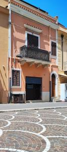 - un bâtiment avec un balcon et une rue pavée dans l'établissement casa Fontana, à Capaci