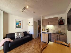 un salon avec un canapé noir et une cuisine dans l'établissement Studio piscine, proche mer, parking privé, à Bandol 5 autres photos