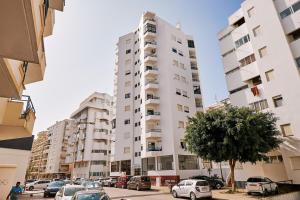 a tall white building with cars parked in a parking lot at Apartment Ricardo-200m zum Meer in Armação de Pêra