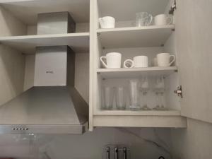 a white cabinet with cups and mugs in it at George and Helen's Studio in Corfu
